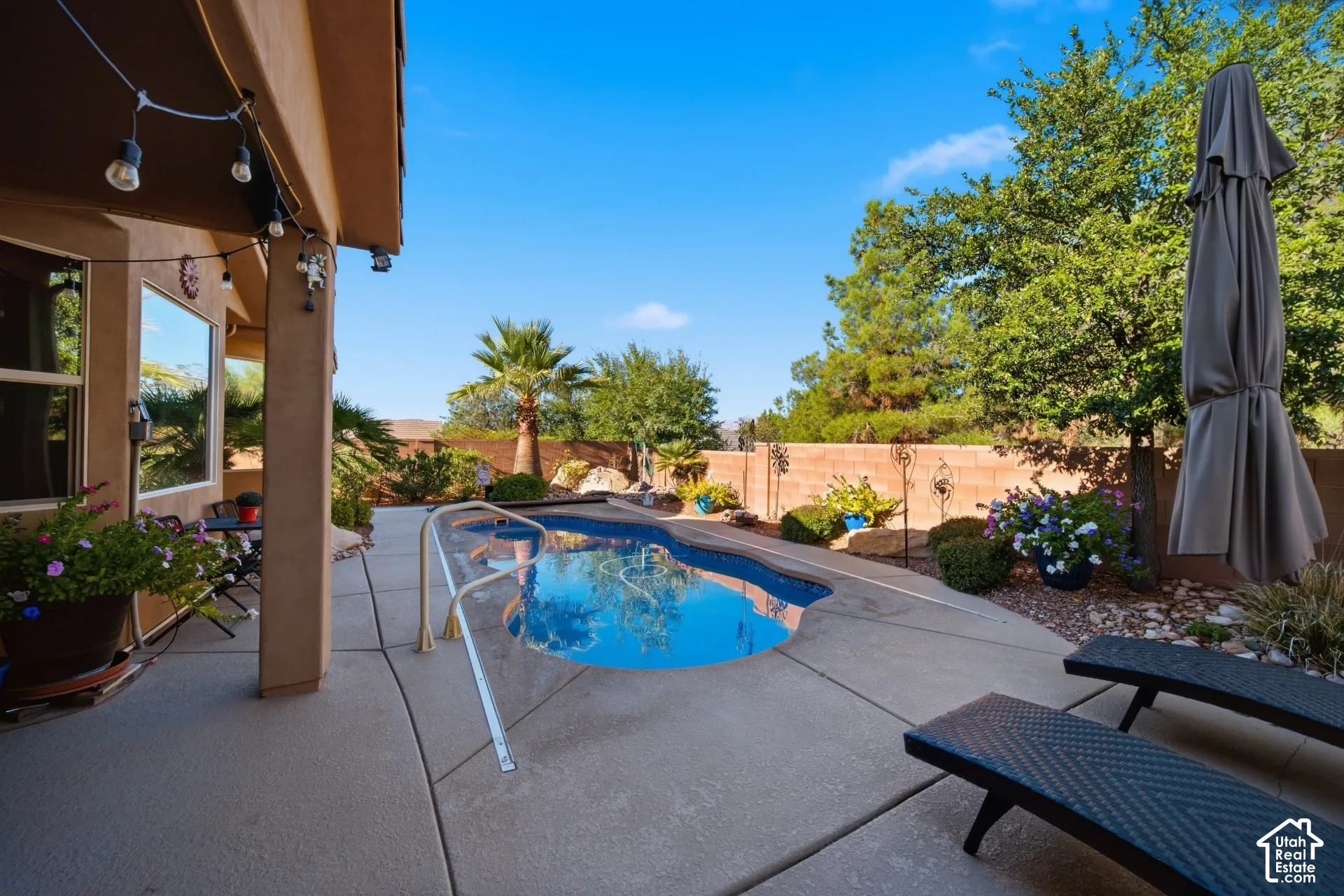 Concrete patio featuring a built-in swimming pool with an integrated handrail