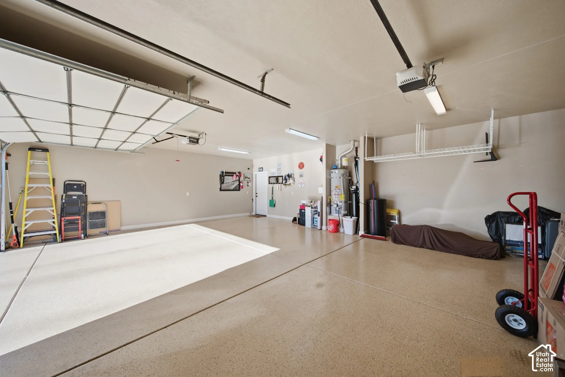 Spacious garage featuring a durable epoxy floor, overhead lighting, and built-in shelving