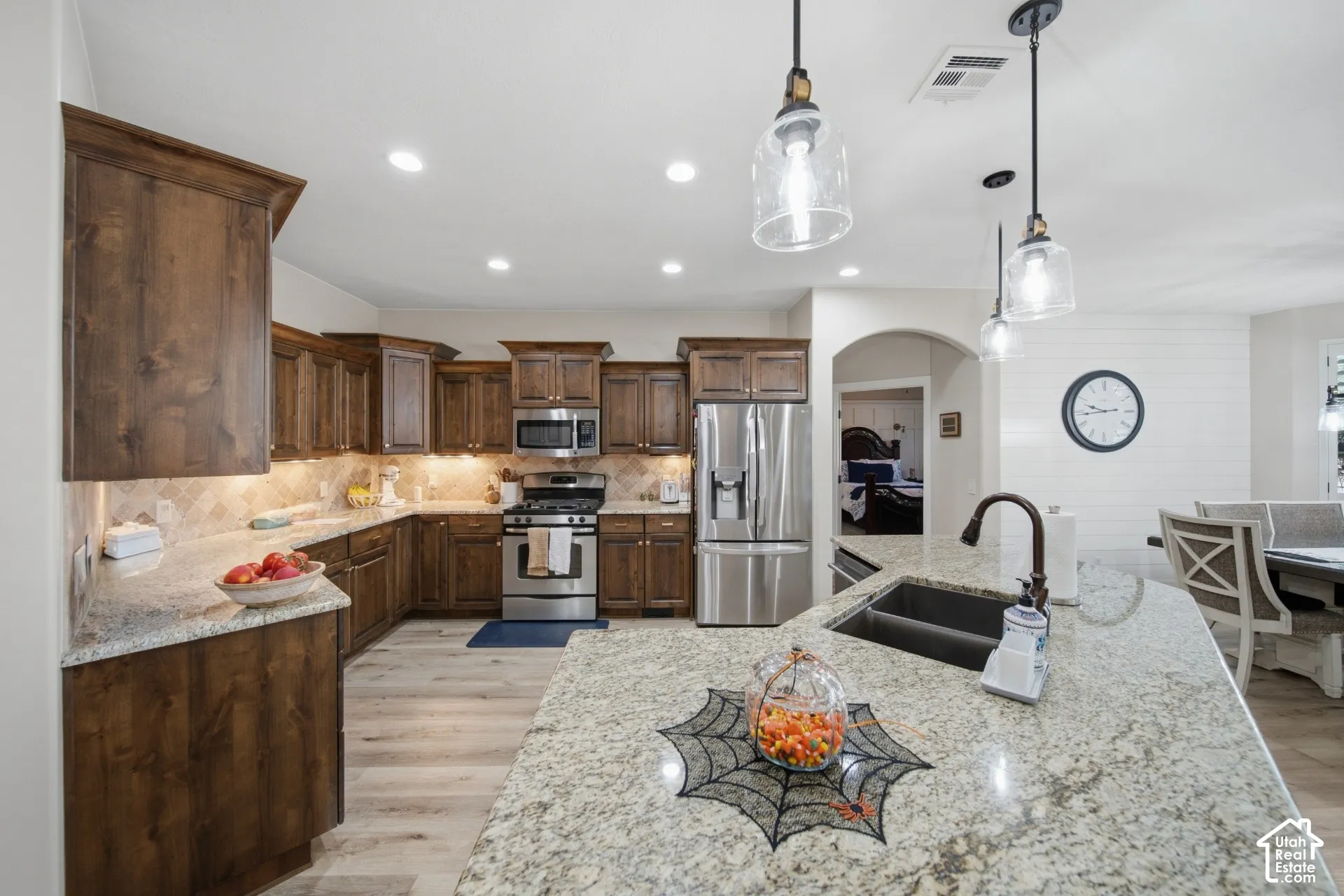 Kitchen featuring wood-finish cabinetry, stainless steel appliances, light-toned countertops, and pendant lighting