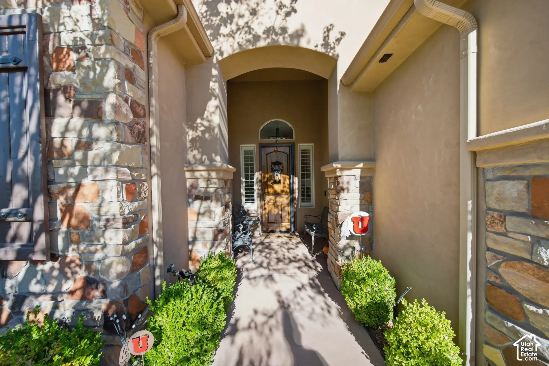 Arched entryway with a wood-finish front door, accented by stone veneer and stucco exterior finishes
