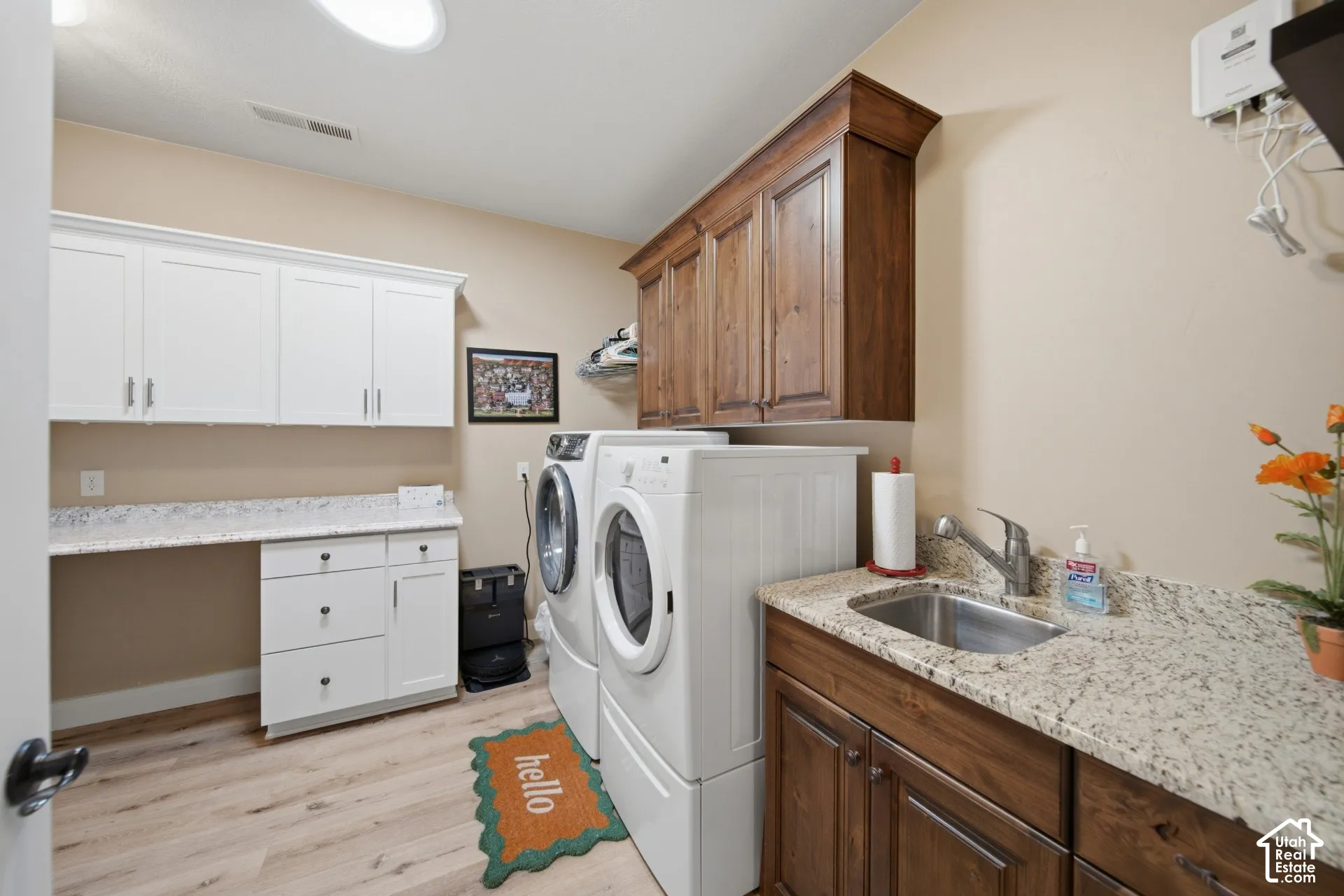 White upper cabinetry, wood-finish upper cabinetry, light-toned wood-finish flooring, built-in sink, and light-toned countertop