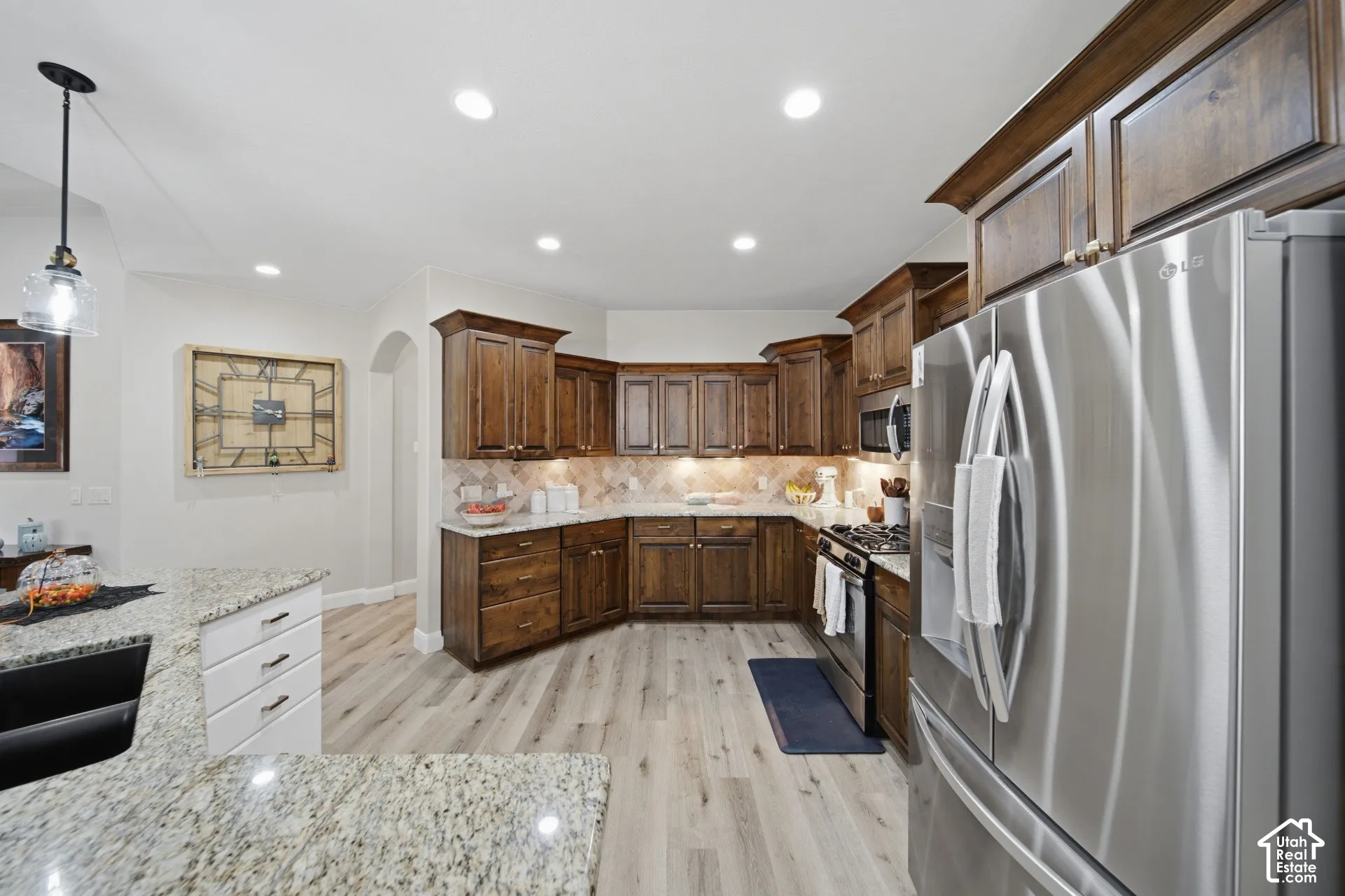 Kitchen featuring wood cabinetry, light-toned wood-finish flooring, stainless steel appliances, granite countertops, and recessed lighting