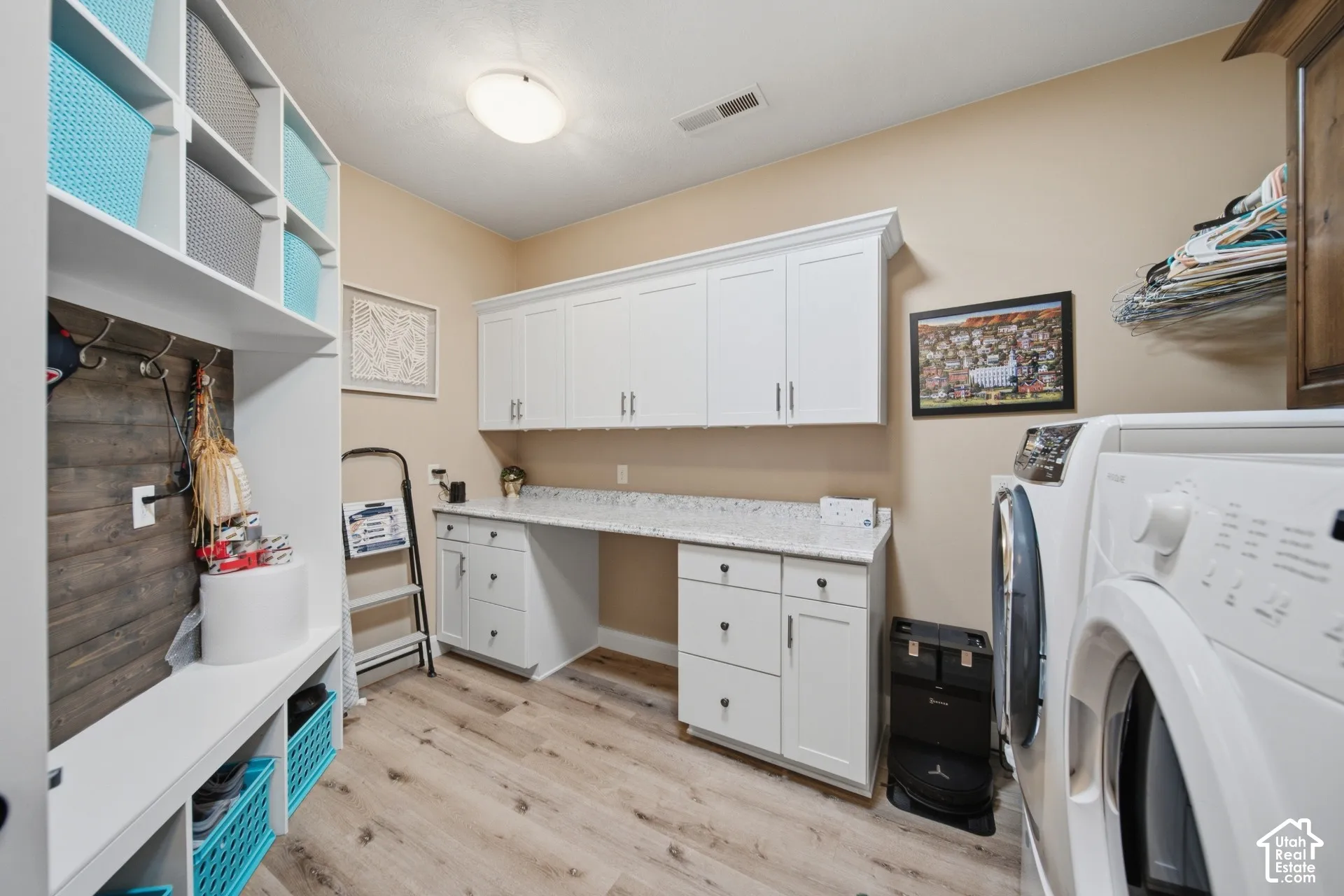 Built-in storage shelving, wood-finish flooring, white cabinetry, integrated countertop, and recessed lighting