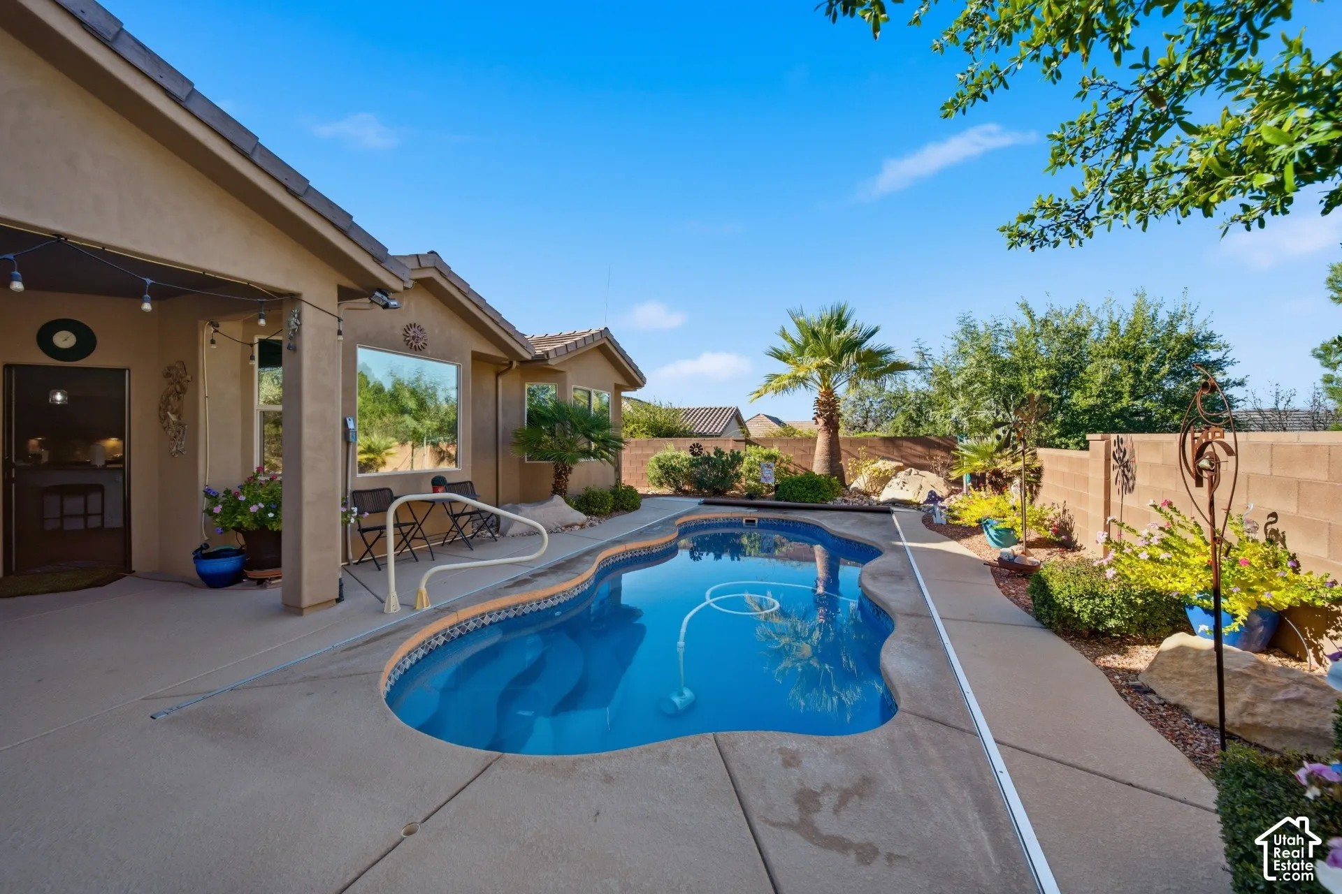 Freeform swimming pool with integrated steps, concrete pool deck, and perimeter landscaping