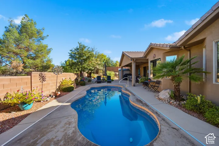 Curved swimming pool with an integrated spa, surrounded by concrete decking and xeriscaping