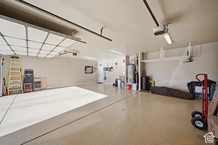 Spacious garage featuring a durable epoxy floor, overhead lighting, and built-in shelving