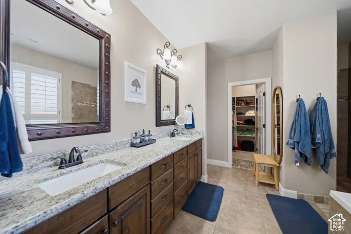Double vanity with granite countertops, rich wood cabinetry, and dual undermount sinks