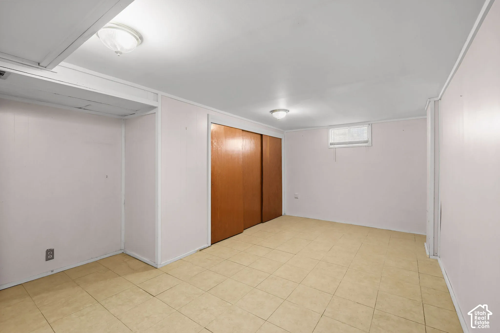 Built-in closet with sliding wood-finish doors, tiled flooring, and flush-mount ceiling lighting