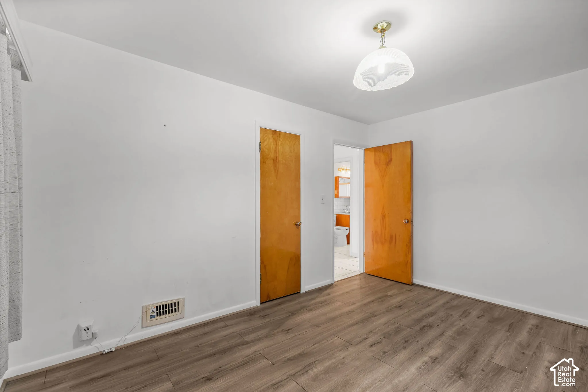 Wood-finish flooring with white walls and a ceiling-mounted light fixture