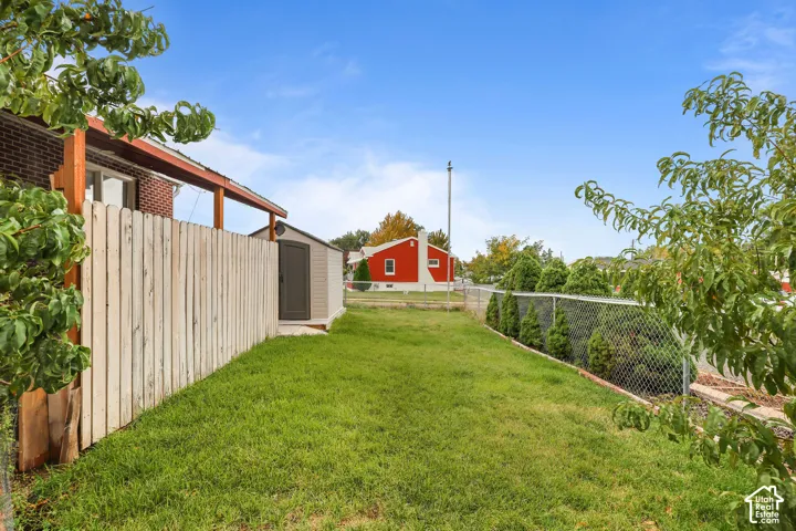 Expansive grassy yard with a privacy fence, chain-link fencing, and mature trees