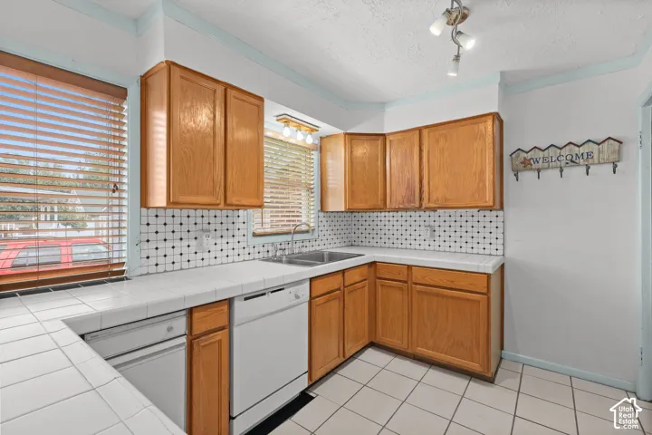 Kitchen featuring wood cabinetry, white tile countertops, white tile flooring, and integrated white appliances