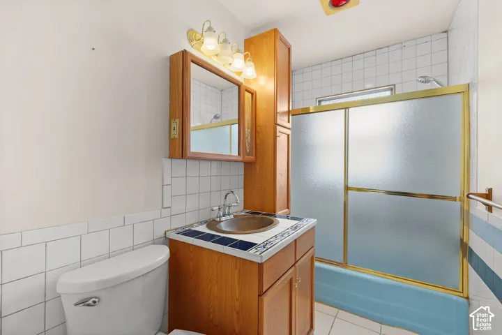 Full bathroom featuring a vanity with tile countertop, integrated sink, and wood-finish cabinetry