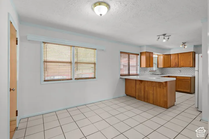 White tile flooring, wood cabinetry, track lighting, and a white tile backsplash