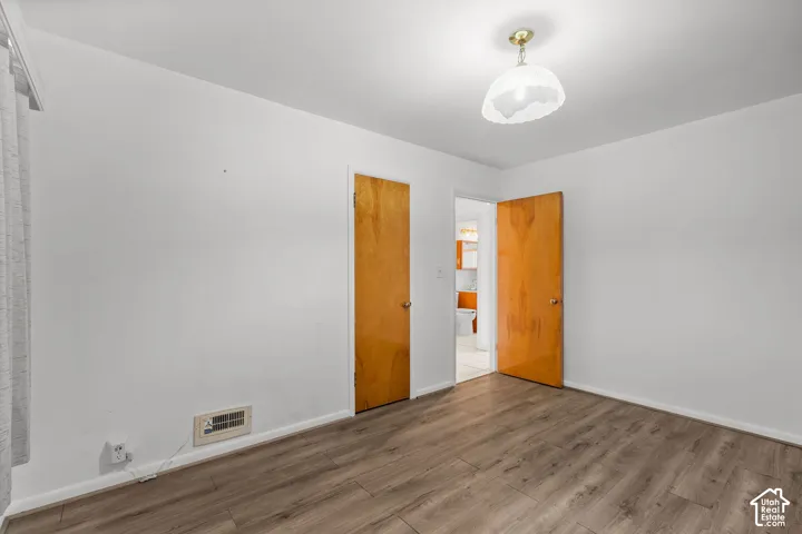 Wood-finish flooring with white walls and a ceiling-mounted light fixture