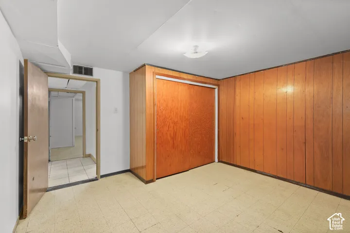 Wall-to-wall wood paneling, wood-finish sliding closet doors, white painted walls, and ceiling-mounted flush light fixture