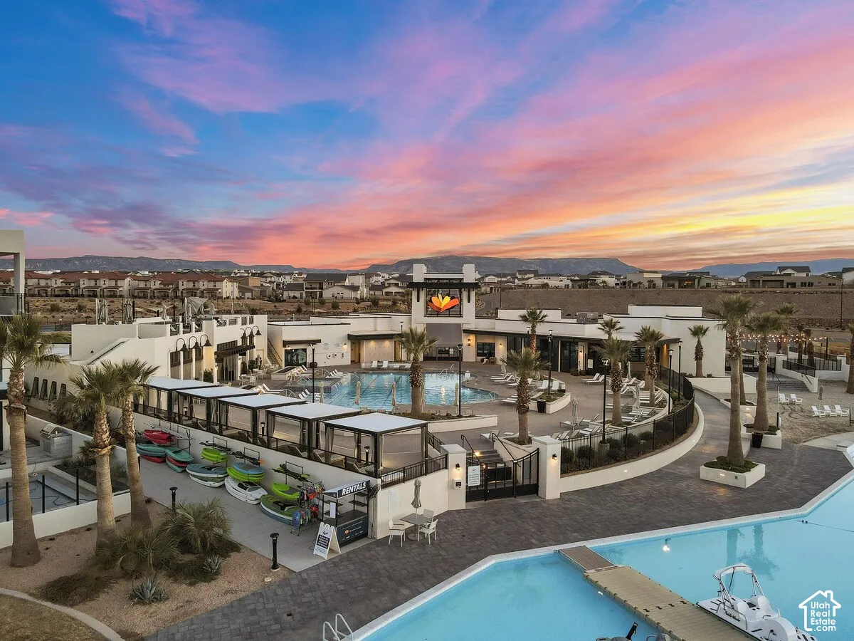 Resort-style community pool with multiple shaded cabanas, extensive paved decking, and integrated palm tree landscaping