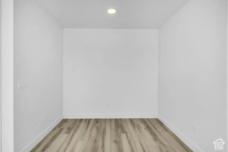 Recessed ceiling lighting illuminates the interior space with wood-finish flooring, white walls, and white trim