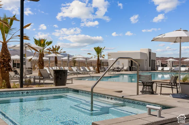 Integrated spa with handrail, large swimming pool, and concrete pool deck