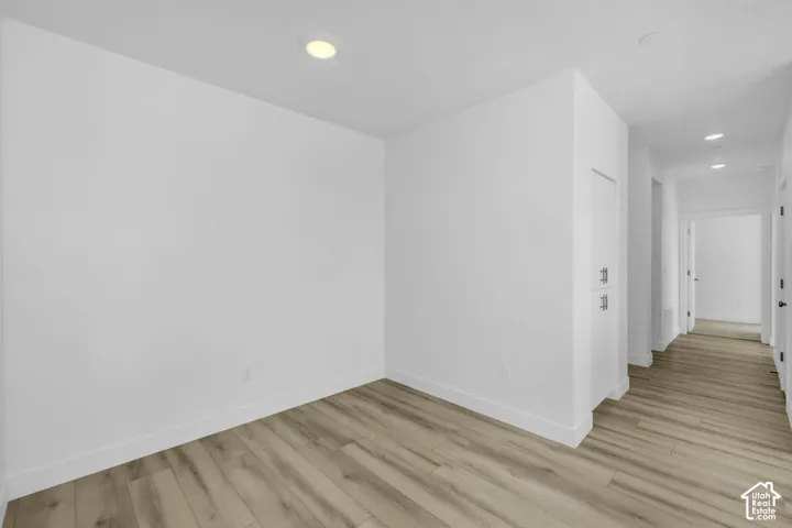 Recessed ceiling lighting, light wood-finish flooring, white walls, built-in storage cabinetry with brushed nickel hardware, and white trim