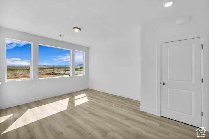 Bright interior with multiple windows, wood-finish flooring, and a two-panel door