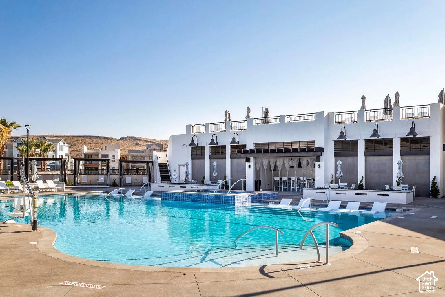 Resort-style swimming pool with integrated lounge seating, poolside bar area, and a surrounding concrete deck
