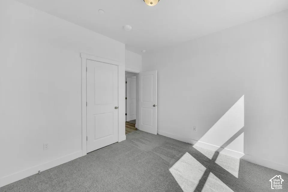 Neutral-toned carpeting, white walls, and white trim throughout