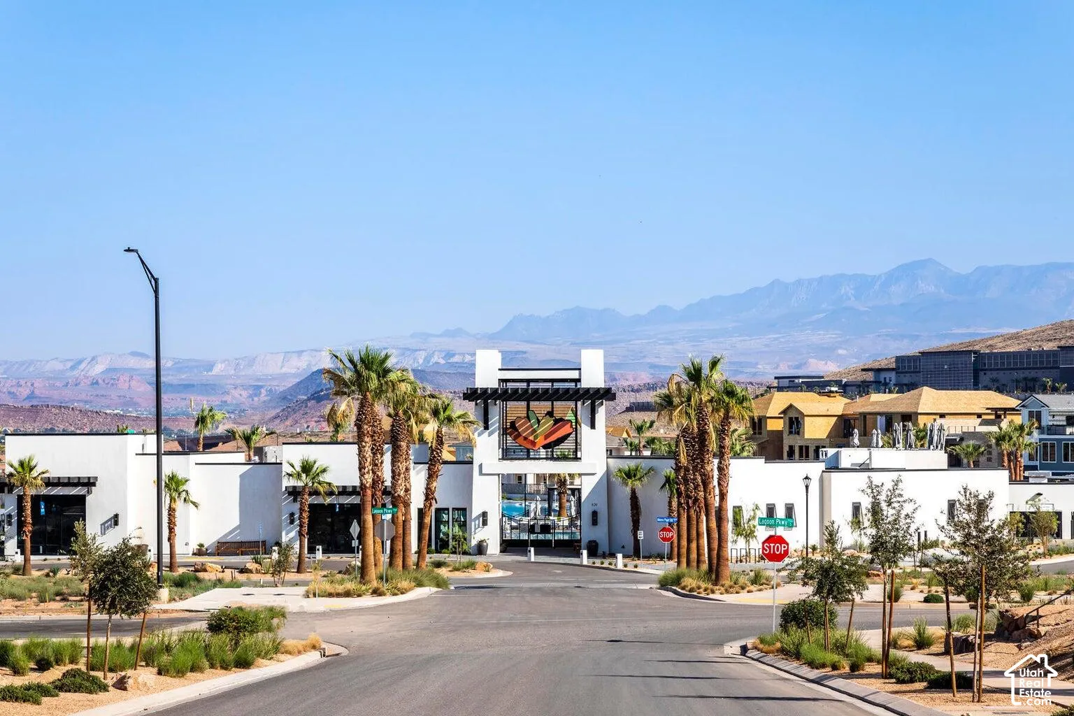 Modern architecture, desert landscaping, mountain backdrop, palm trees, paved roadway