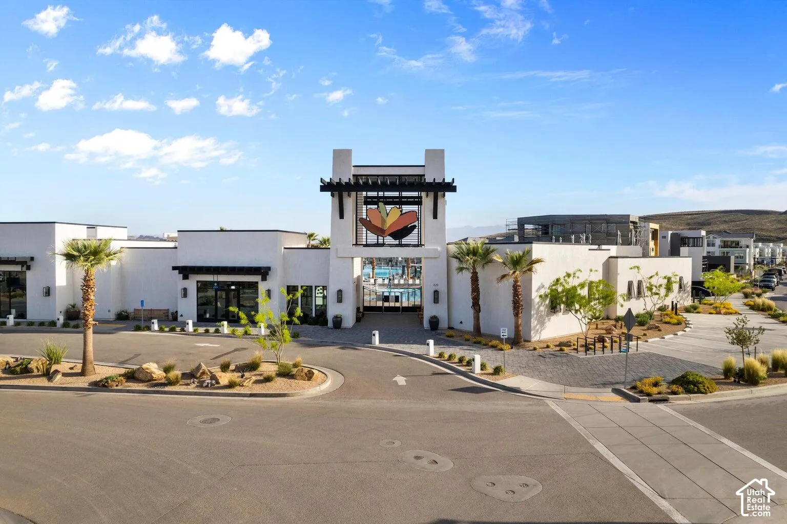 Modern white stucco exterior with dark wood architectural accents, integrated central entryway, and desert landscaping