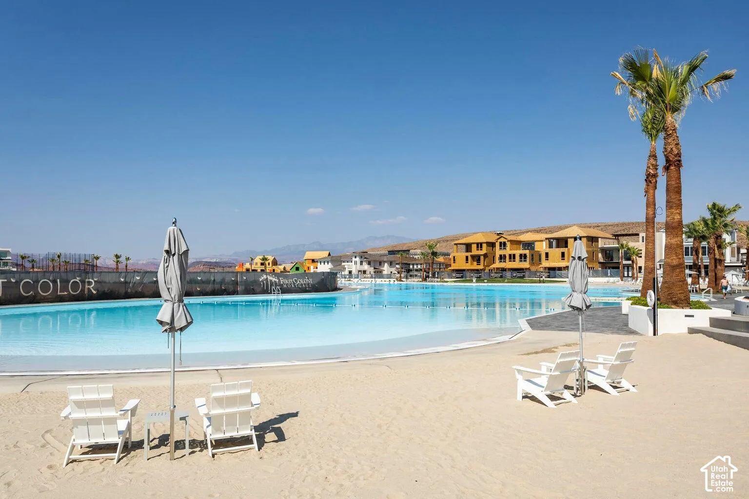 Expansive blue lagoon bordered by a sandy beach and mature palm trees