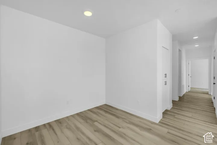 Recessed ceiling lighting, light wood-finish flooring, white walls, and built-in storage with silver-tone hardware