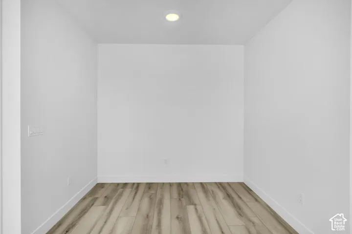Recessed ceiling lighting, wood-finish flooring, and white walls