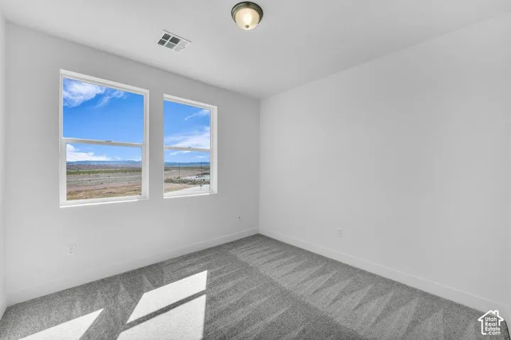 Bright room featuring two large windows, neutral wall paint, and patterned carpeting