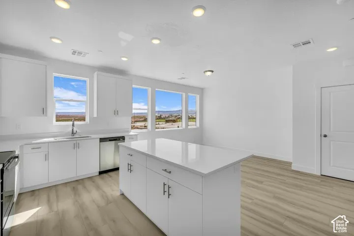 White shaker-style cabinetry with stainless steel hardware, a central island with a white countertop, and wood-finish flooring