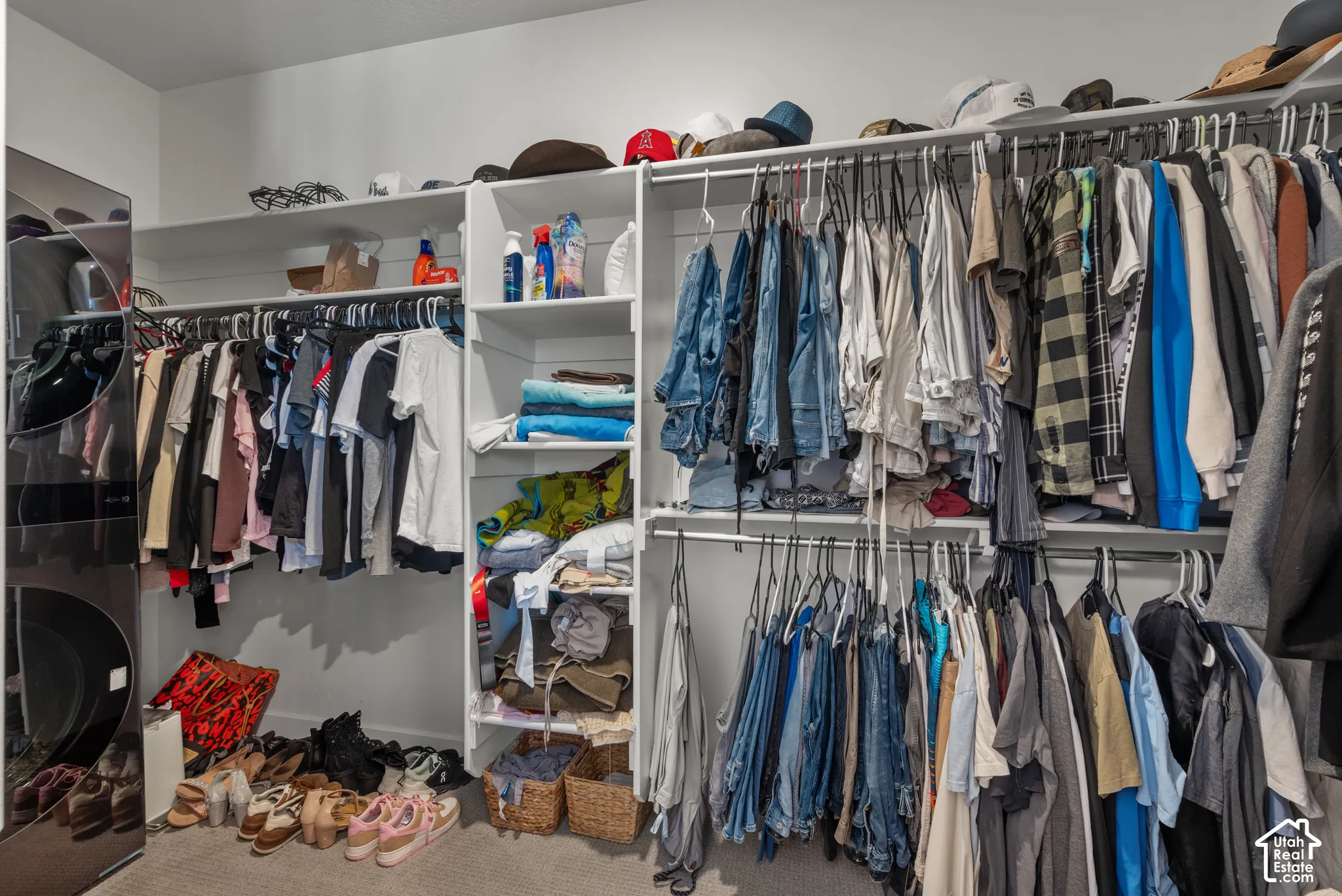 Built-in closet system featuring multiple hanging rods, integrated shelving, and a dedicated laundry area with stacked appliances
