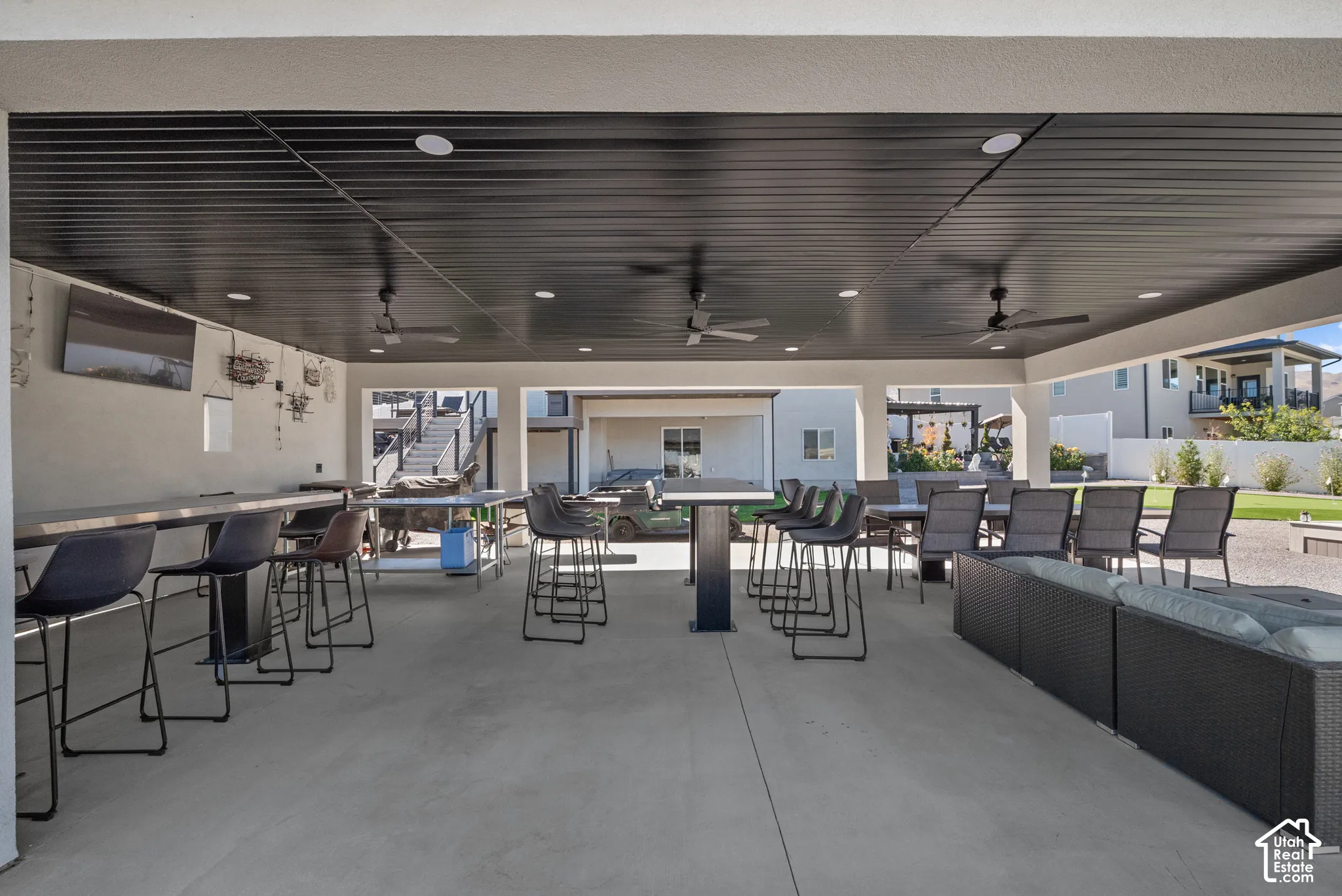 Expansive covered patio with concrete flooring, recessed lighting, and integrated ceiling fans