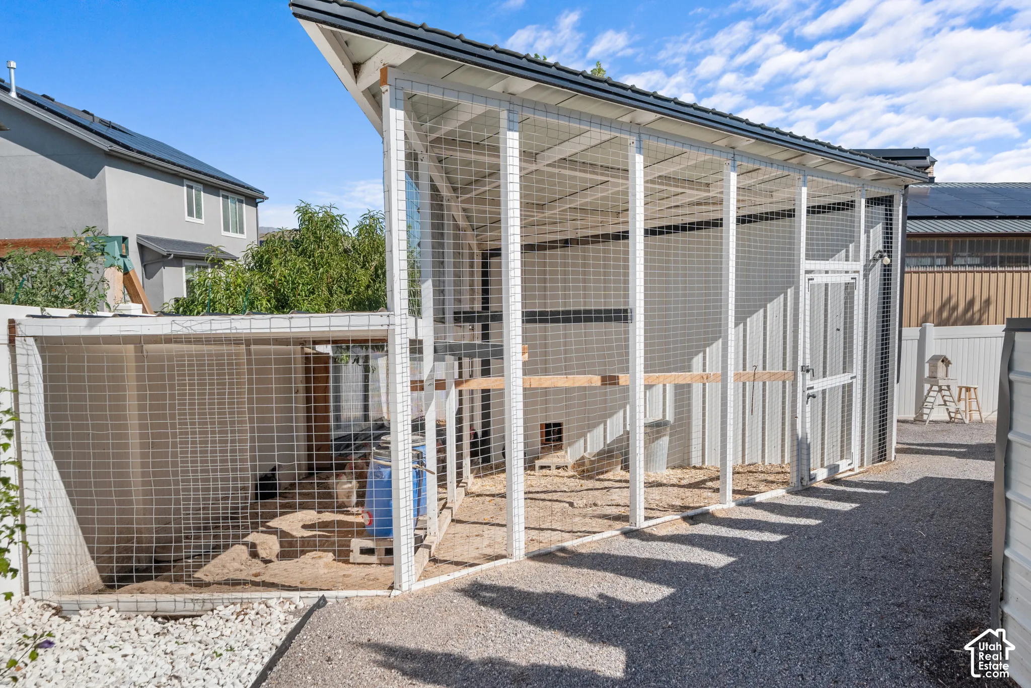 Gravel pathway leading to an enclosed structure with a pitched roof and wire mesh walls