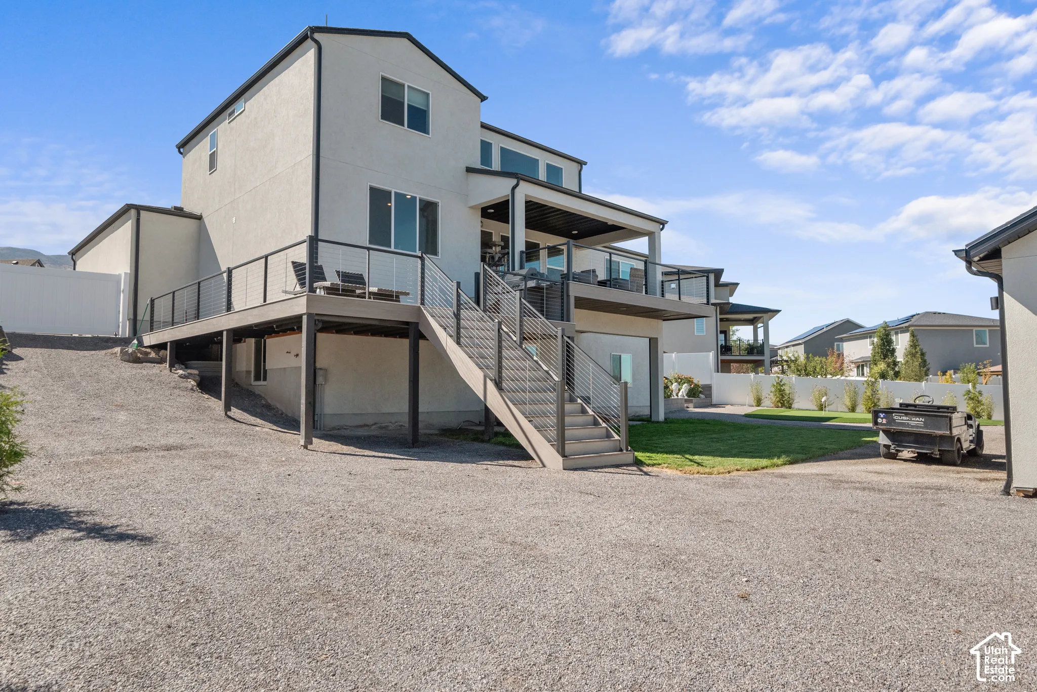 Contemporary stucco exterior with a multi-level deck featuring cable railings and composite decking