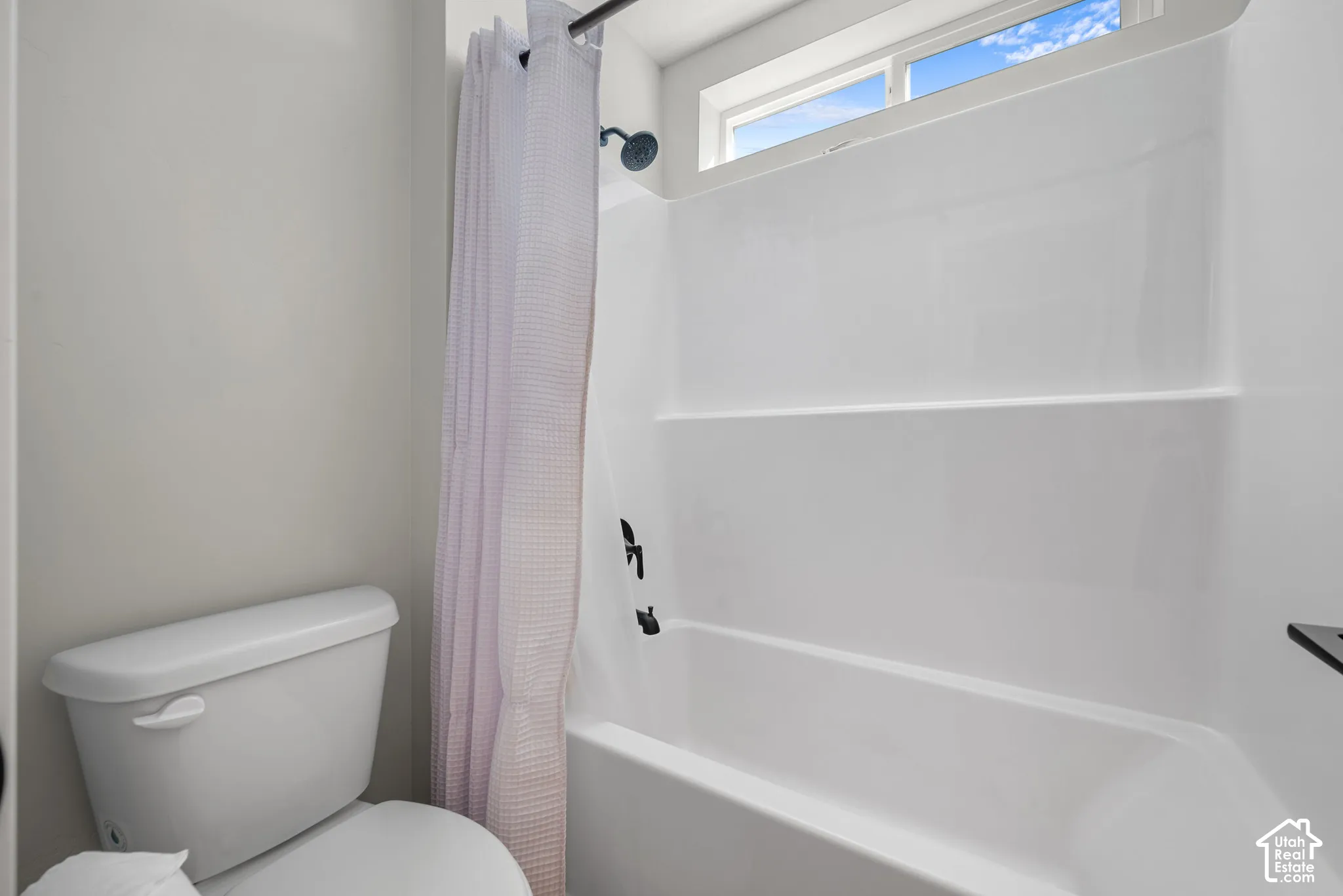 White acrylic tub and shower combination with dark bronze fixtures
