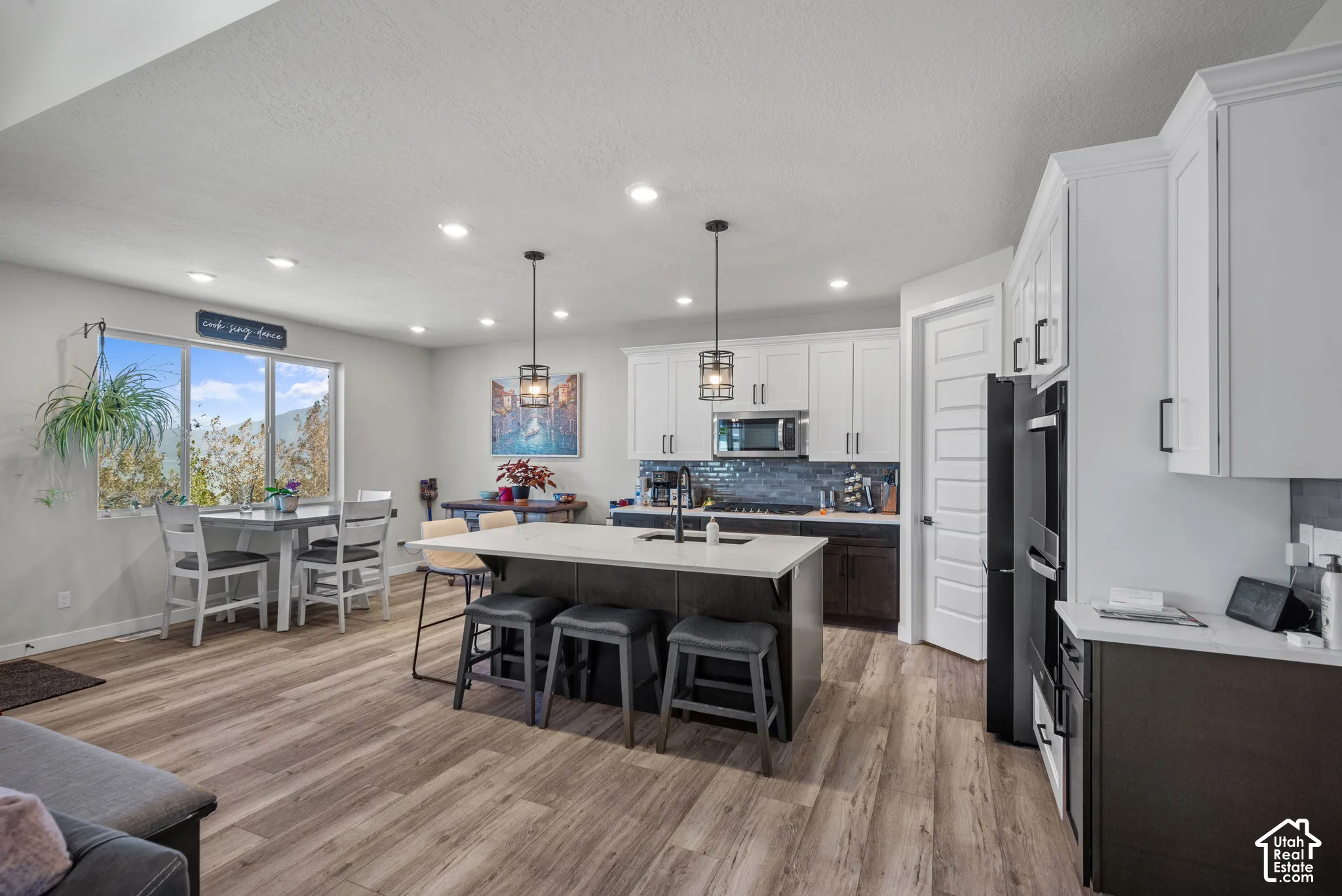 Open-concept living space with wood-finish flooring, recessed lighting, and a kitchen island featuring a light-toned countertop