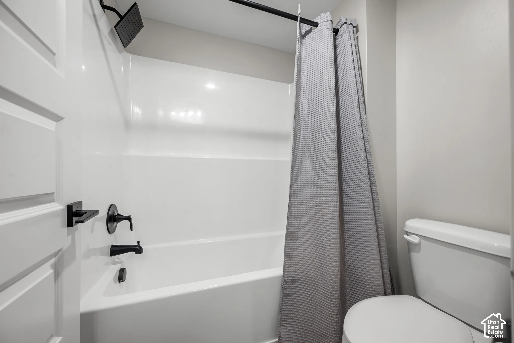 White bathtub with matte black fixtures and a rain shower head