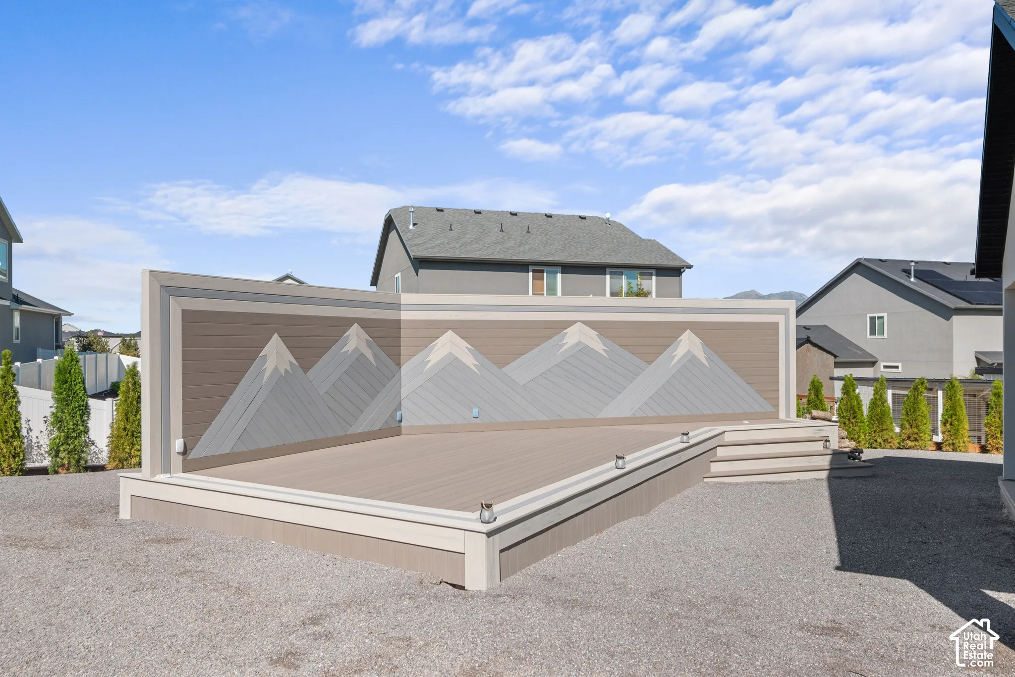 Expansive outdoor deck featuring wood-finish flooring and a decorative mountain-themed privacy wall