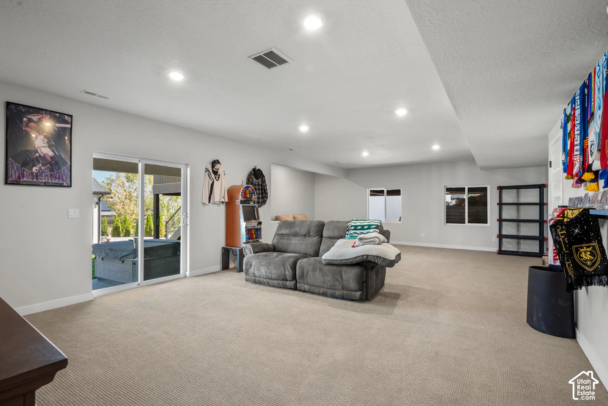 Expansive carpeted room with recessed lighting, multiple windows, and sliding glass doors leading to an outdoor patio