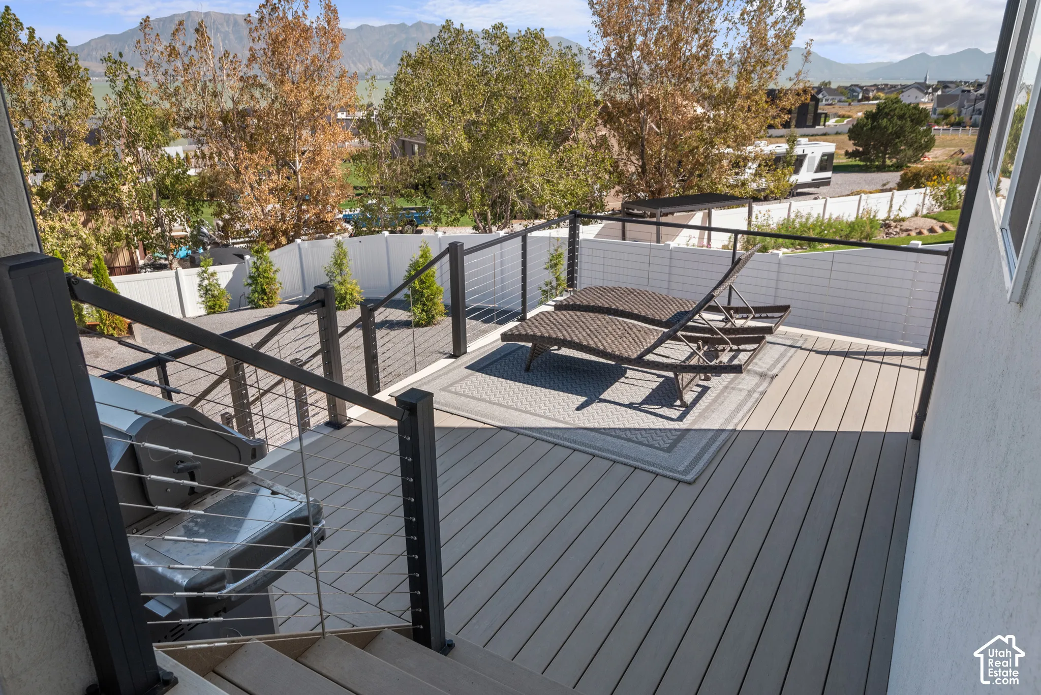 Spacious outdoor deck featuring light-toned composite decking, contemporary cable railings, and a solid privacy wall