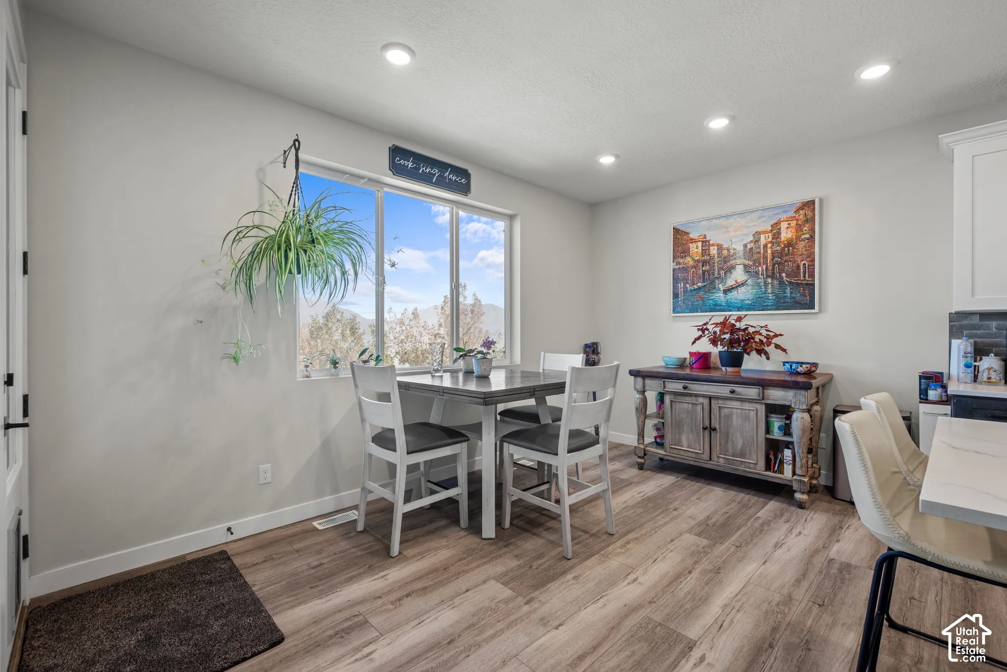 Recessed lighting, wood-finish flooring, white walls, large window, and a built-in cabinetry