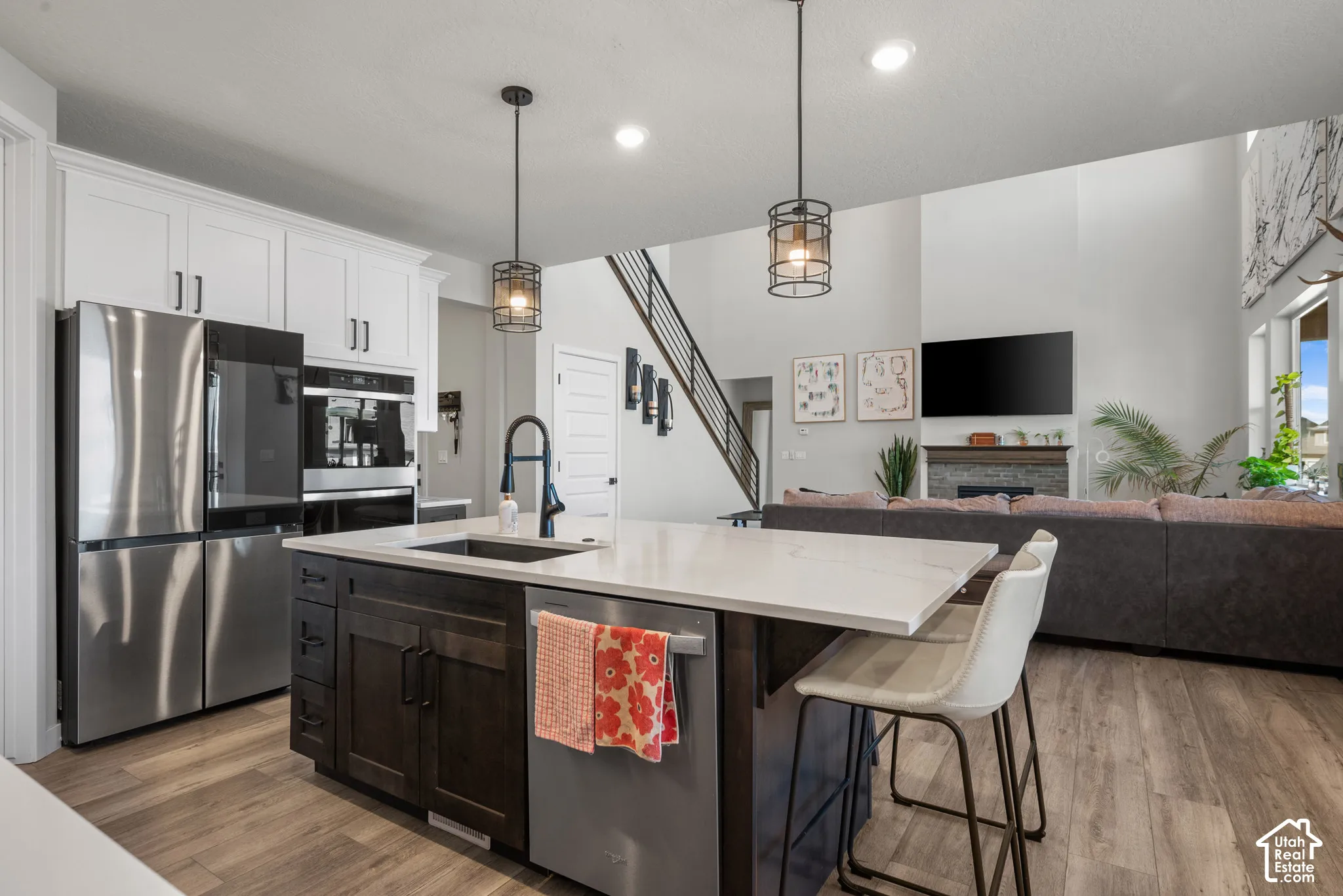 Open concept kitchen featuring an island with seating, stainless steel appliances, white cabinetry, and wood-finish flooring