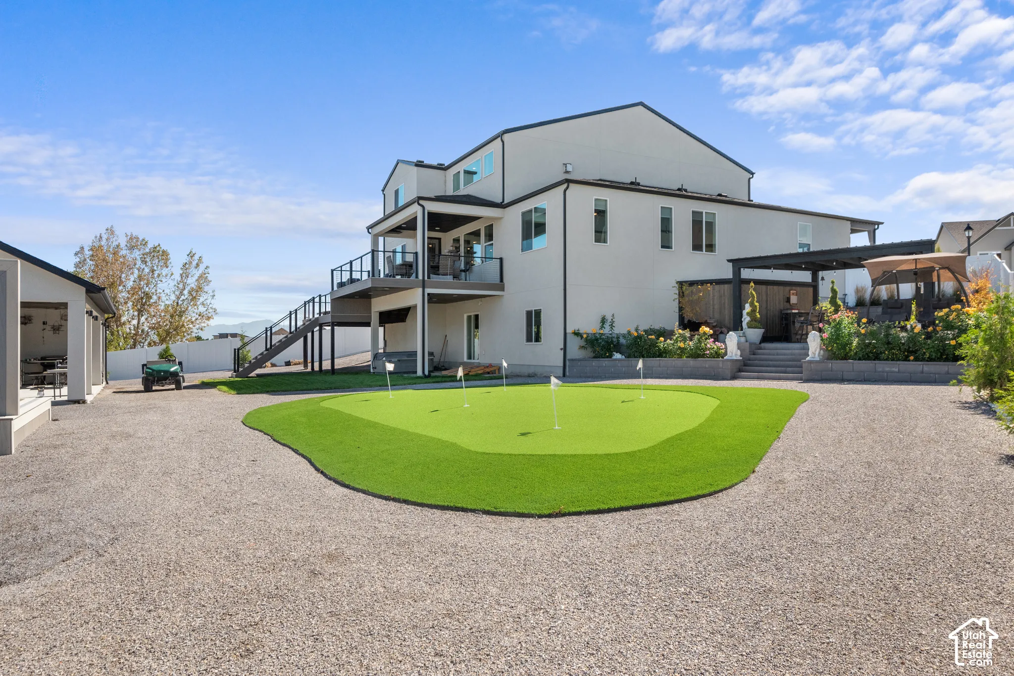 Expansive gravel driveway leading to a putting green with multiple flags
