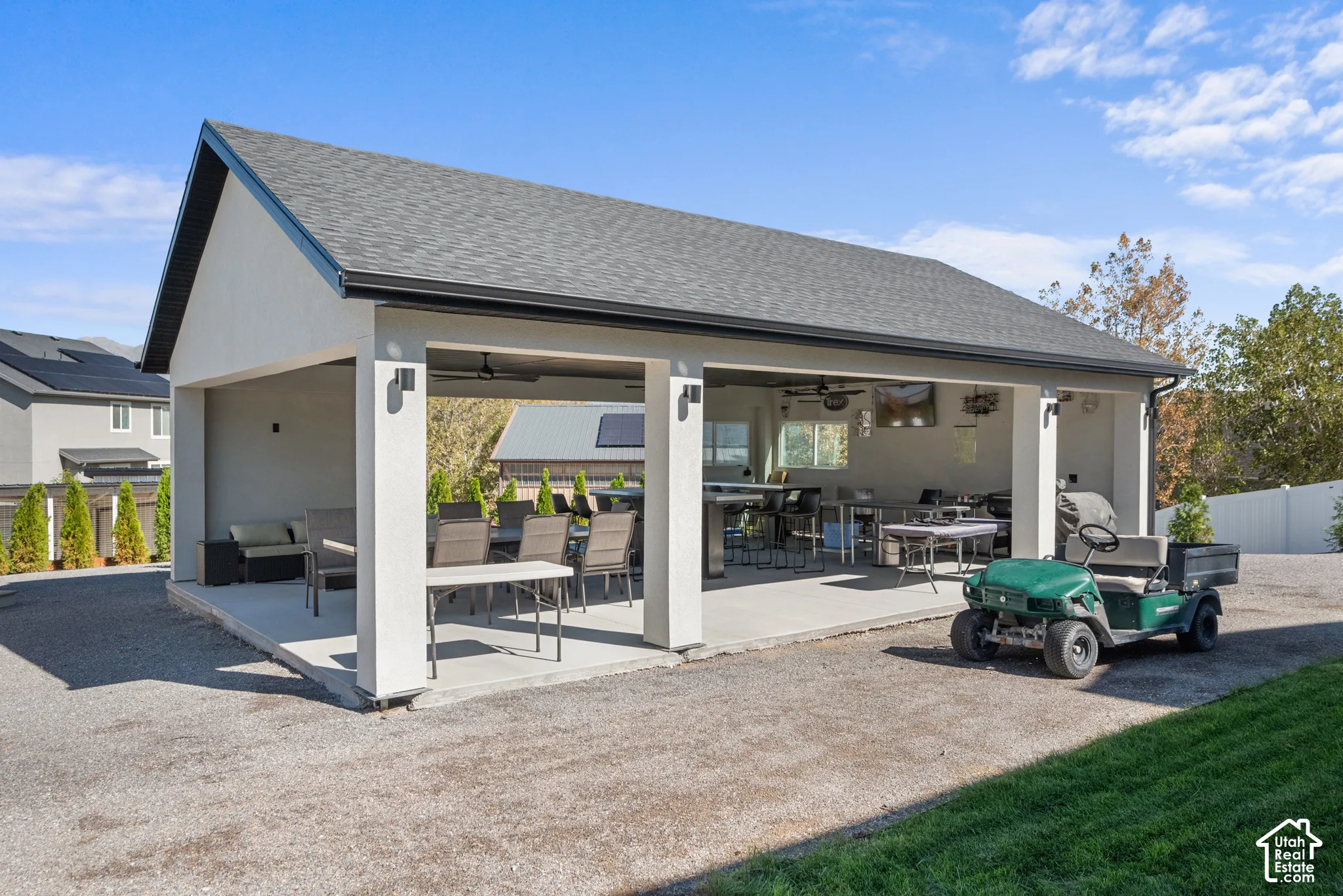 Covered patio structure with a gabled roof, concrete flooring, and outdoor lighting fixtures