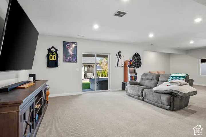 Carpeted flooring, recessed lighting, white painted walls, and sliding glass door access to the exterior