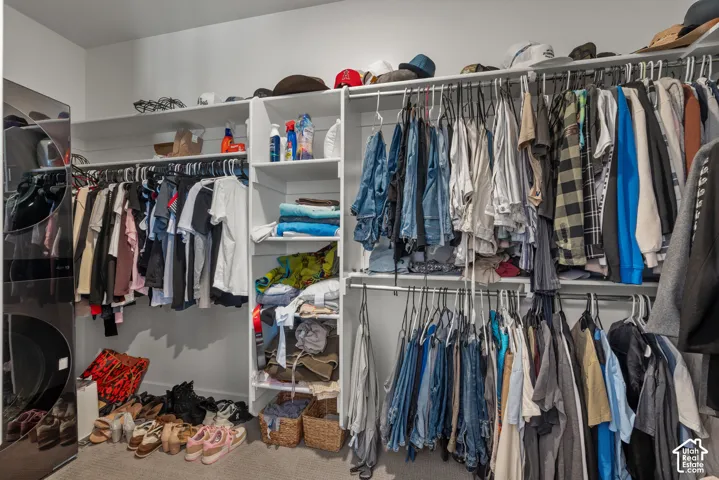 Built-in closet system featuring multiple hanging rods, integrated shelving, and a dedicated laundry area with stacked appliances