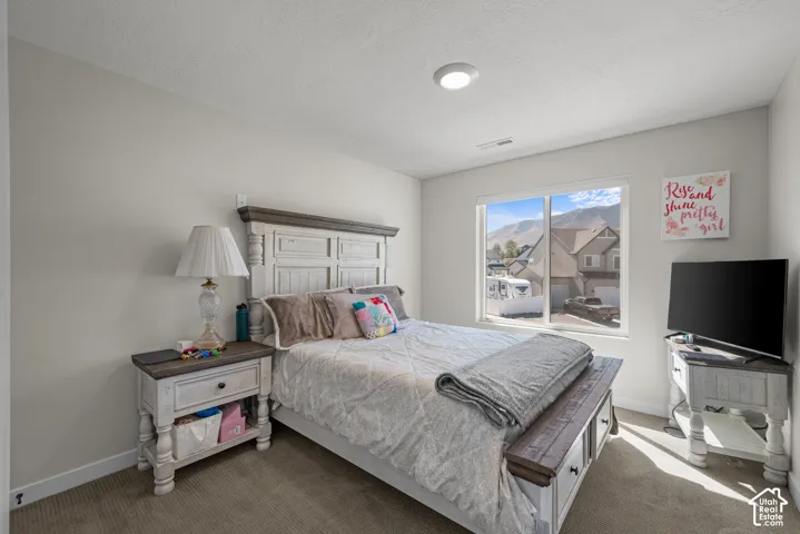 Recessed ceiling light fixture, carpeted flooring, large window with mountain scenery, and light-toned wall paint